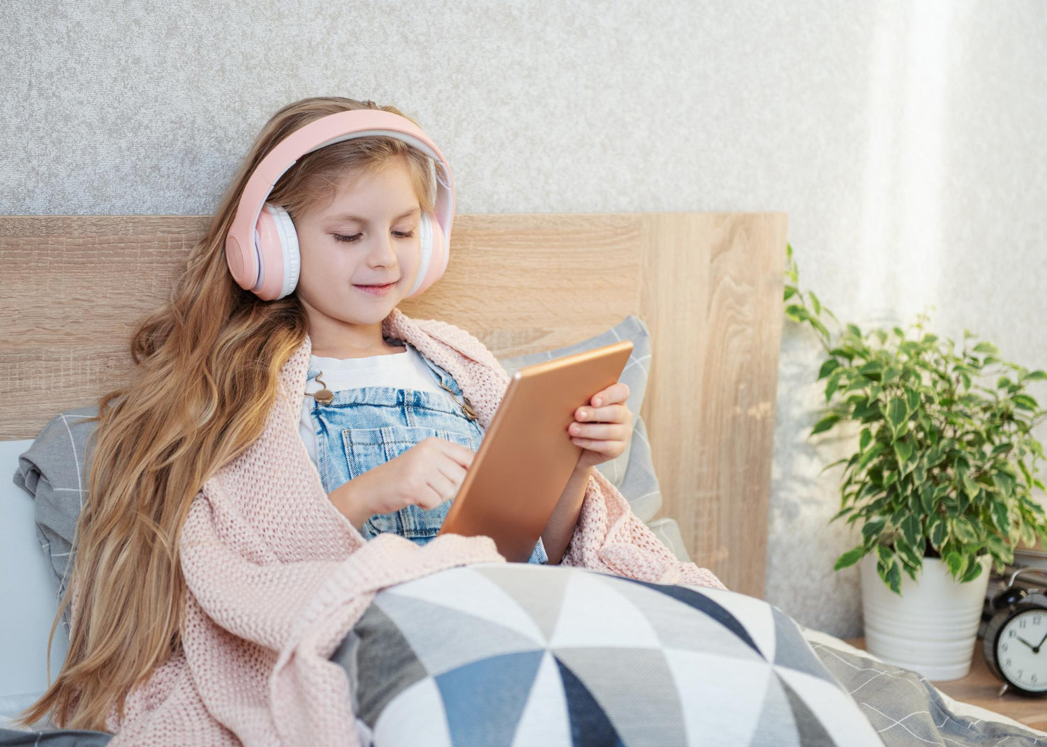 Girl with headphones on listening to an audio book whilst reading an ebook on a tablet