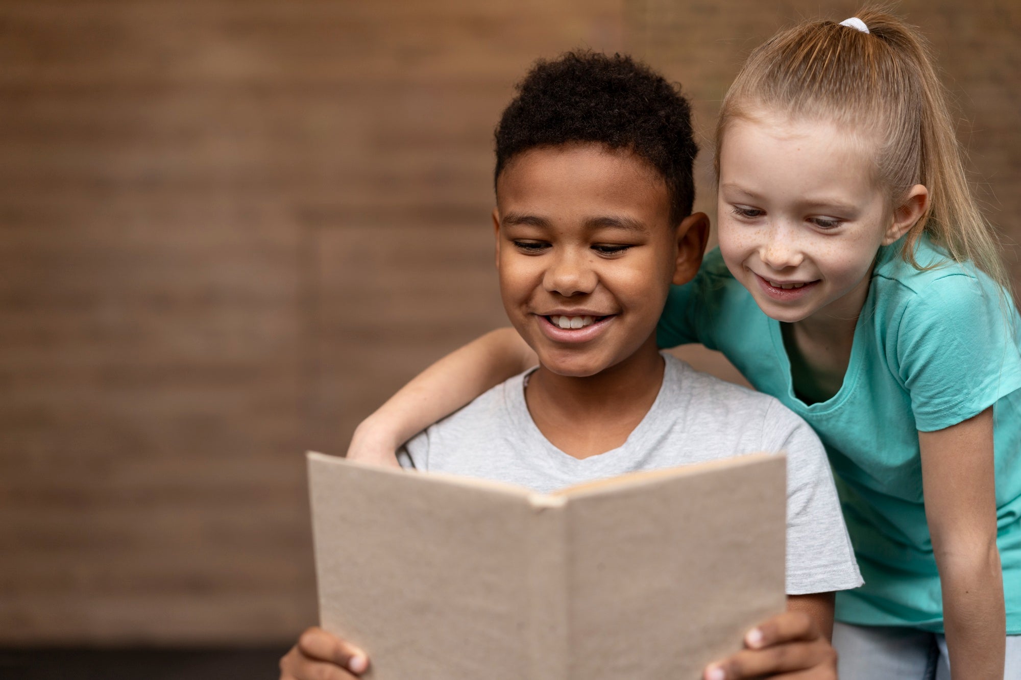 Two children reading a book smiling learning about emotional awareness