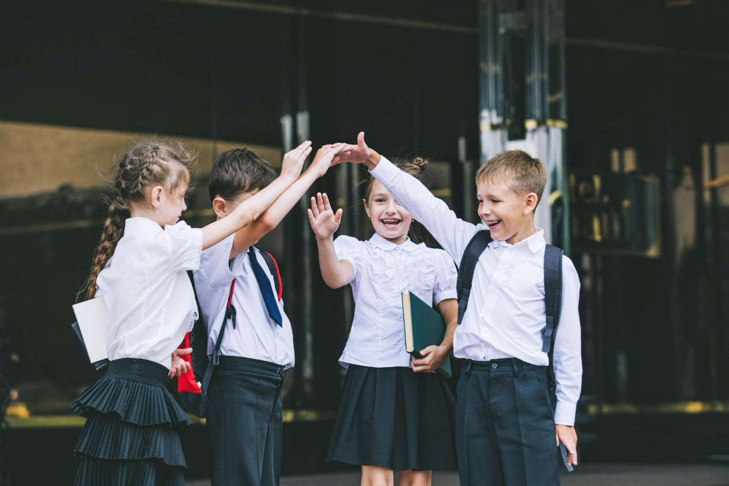 Photo of school children high fiving and smiling to illustrate the role of schools in nurturing youth emotional support