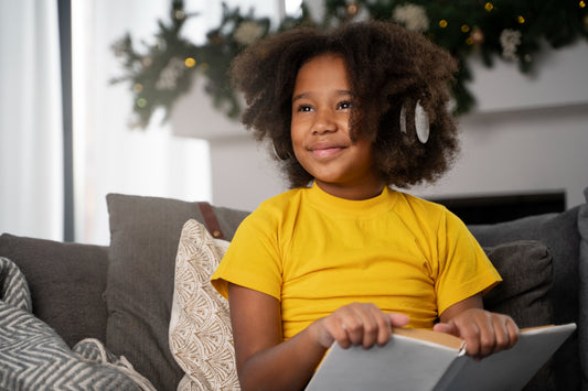 Young girl in a yellow t-shirt reading a children's mental health book and smiling whilst listening to music